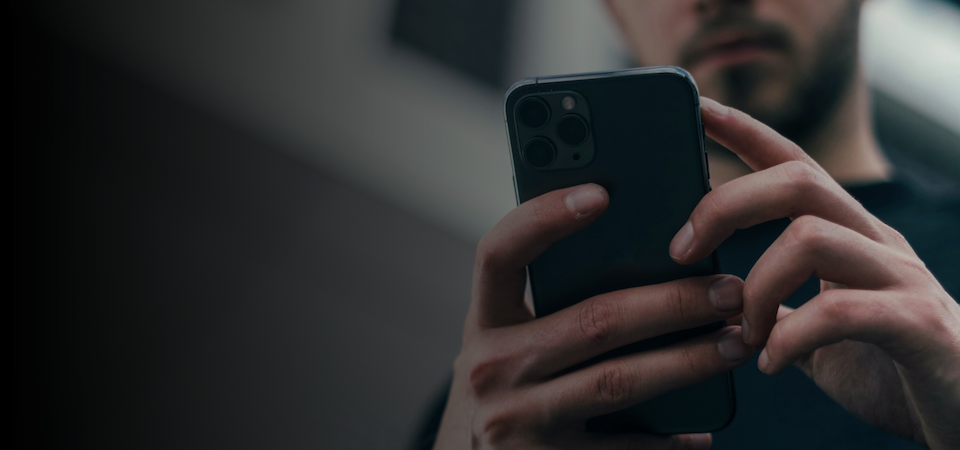 Person nutzt eine Customer App auf dem Smartphone, ergänzt durch ein digitales Interface für Self-Service-Portale und vernetzte Services.